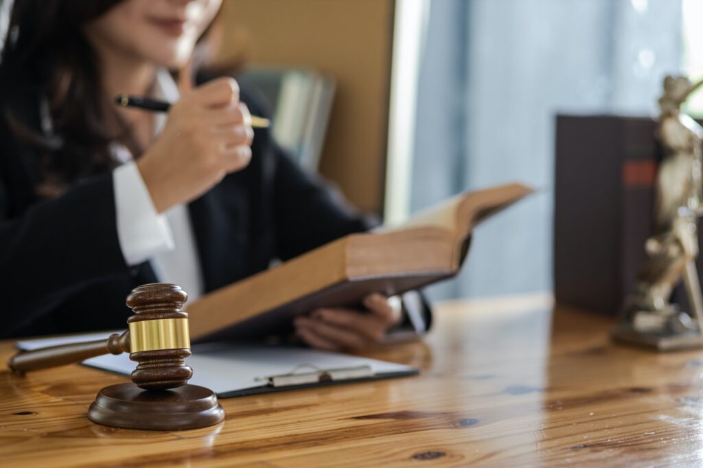 Female lawyer working in a law office reading a law book on the desk.